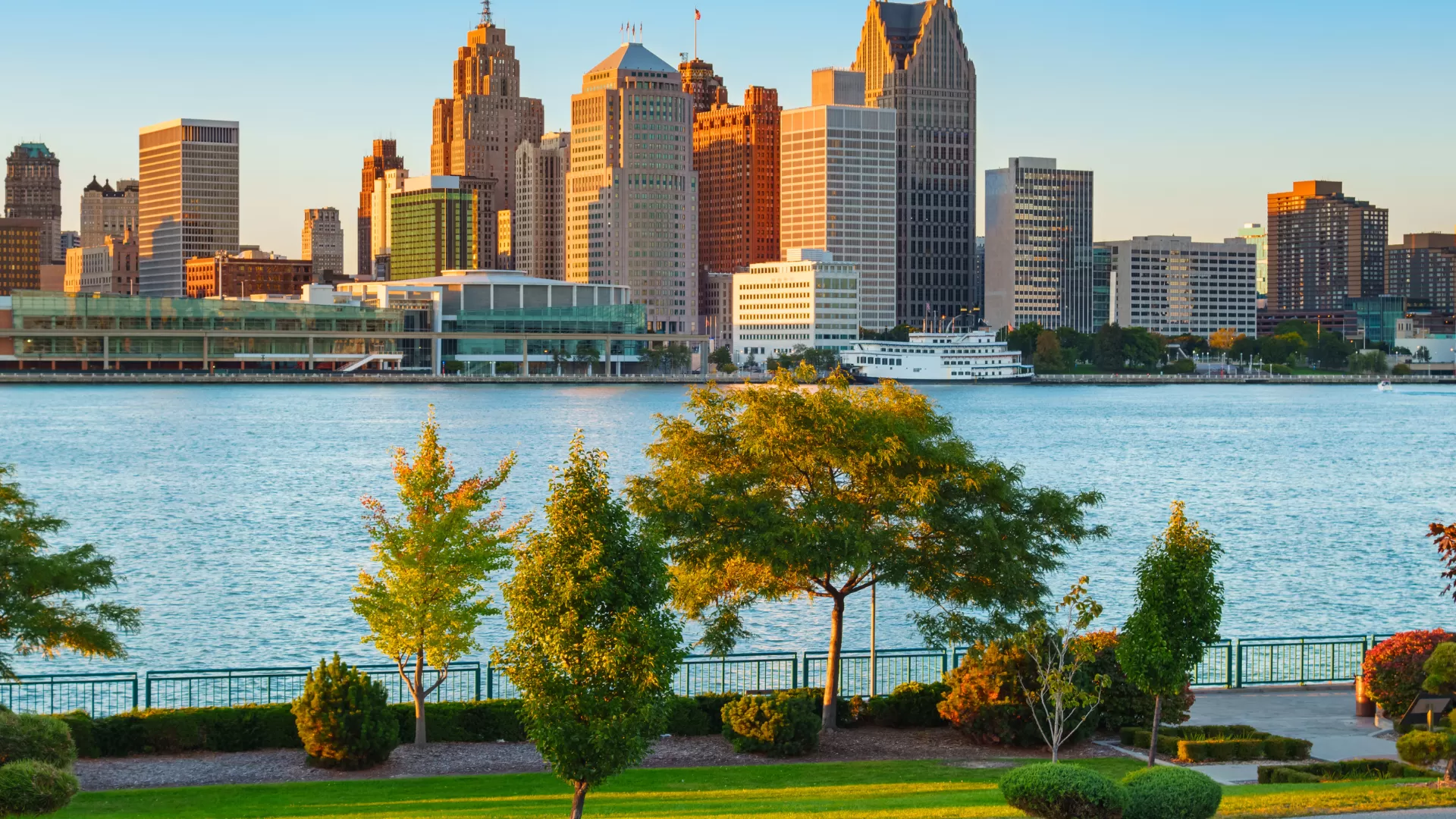 Detroit Skyline seen from across the river with lots of green trees and green grass in the foreground